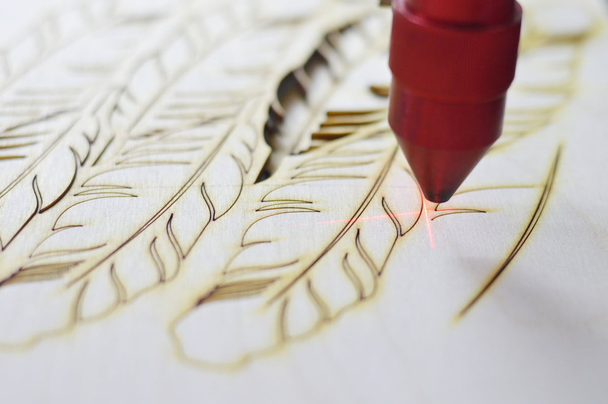 a laser cutting a wood with a red pen